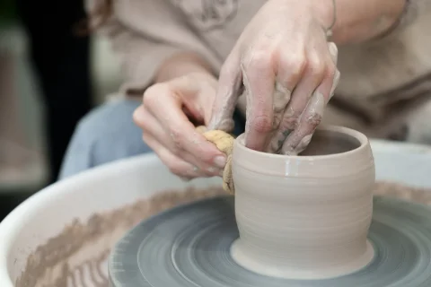 Detail rukou tvarujících nádobu na hrnčířském kruhu v ateliéru Grohova